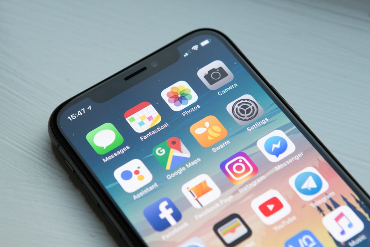 iPhone posé sur une table, écran d'accueil rempli d'applications